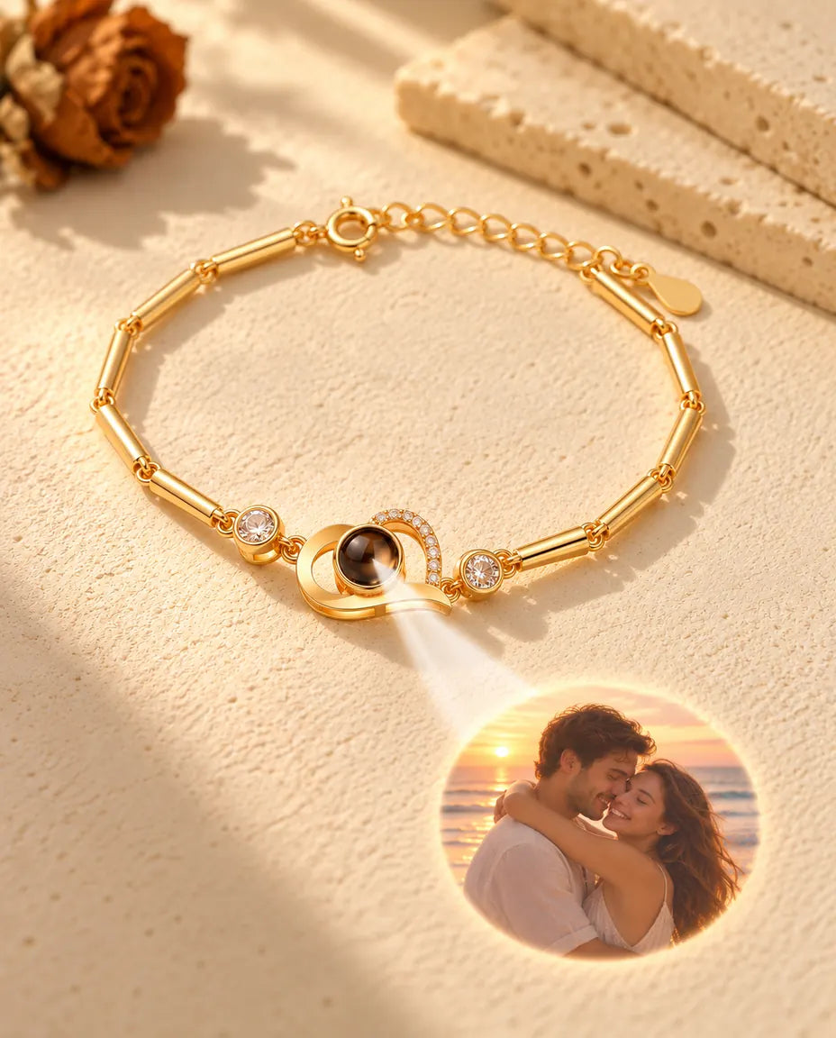 Light through the brown stone of the gold tone heart charm projects a round photo of a couple at sunset