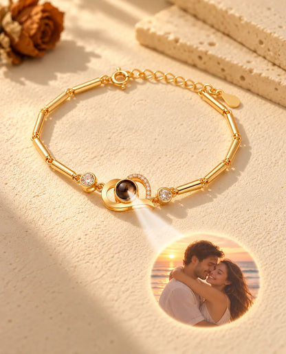 Light through the brown stone of the gold tone heart charm projects a round photo of a couple at sunset