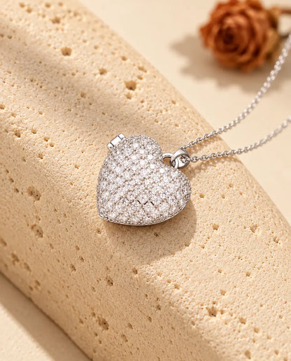 Personalized pave heart photo locket necklace in silver tone covered in cubic zirconia, resting on a travertine block