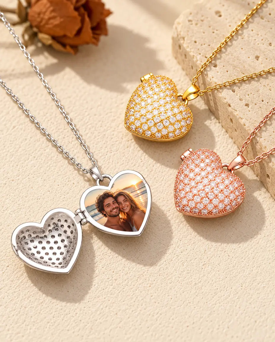 Silver tone pave heart photo locket opened to show a couple photo inside, beside closed gold tone and rose gold tone lockets