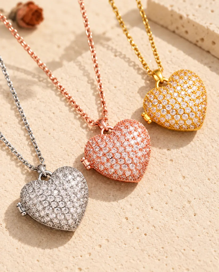 Pave heart photo lockets in silver tone, rose gold tone and gold tone laid diagonally on cream plaster