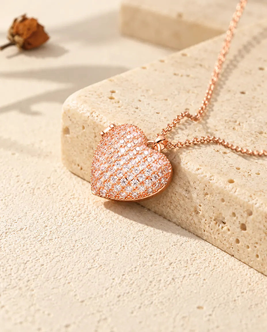 Rose gold tone pave heart photo locket necklace on travertine in warm sunlight