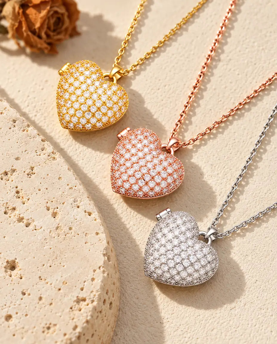 Gold tone, rose gold tone and silver tone pave heart photo lockets stacked beside a travertine slab
