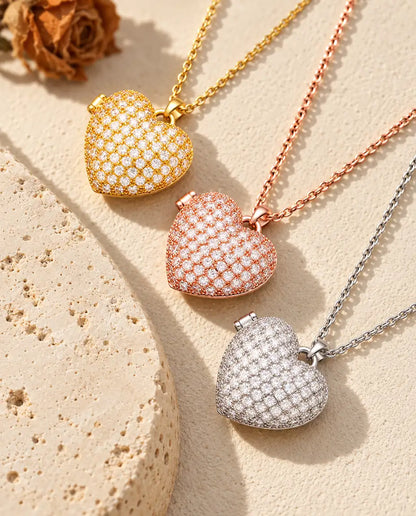 Gold tone, rose gold tone and silver tone pave heart photo lockets stacked beside a travertine slab