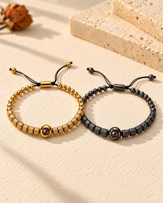 Personalized couples photo projection bracelets, a matching set of two textured bead bracelets in gold tone and black on cream plaster