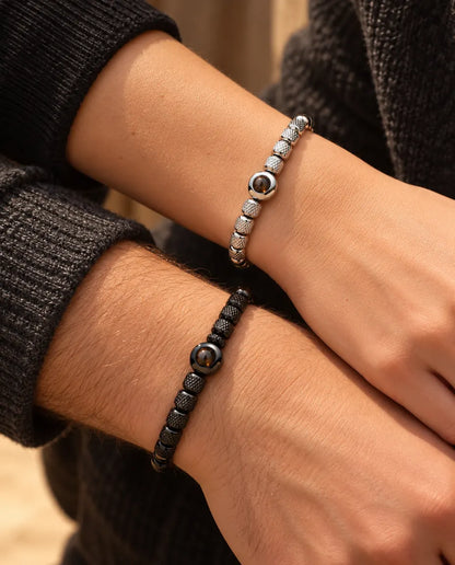 Close-up of his and her wrists with matching silver tone and black projection bead bracelets