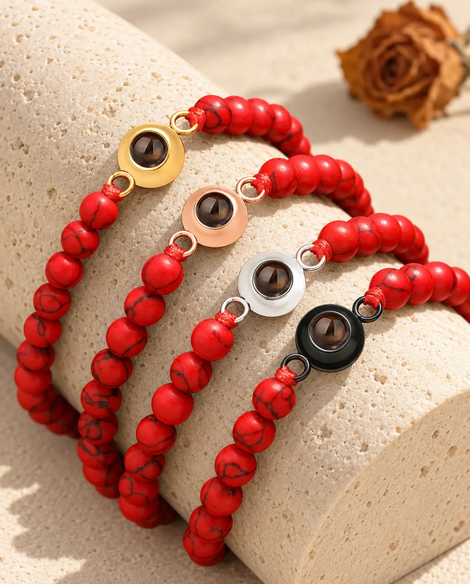 Red marbled bead projection bracelets in four charm colors on a travertine block