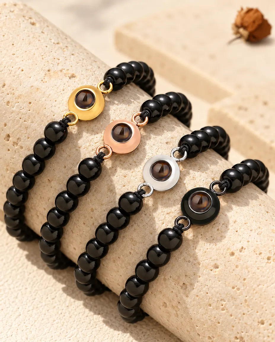 Glossy black bead projection bracelets in all four charm colors on a travertine block