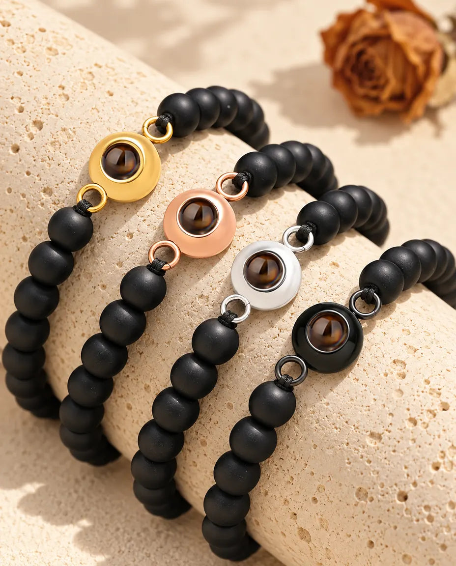 Matte black bead projection bracelets in each charm color draped over travertine