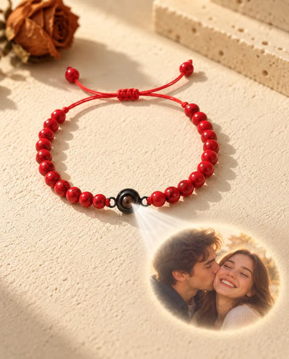 Light through the brown stone of the red bead bracelet projects a photo of a smiling couple