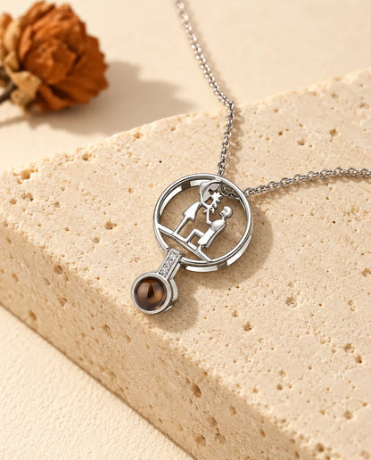 Silver tone proposal projection necklace hanging over a travertine block