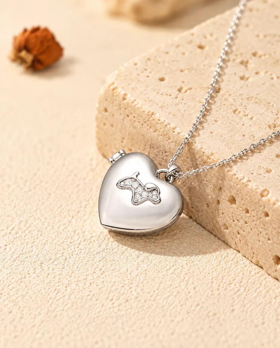 Personalized puppy heart photo locket necklace in silver tone with a cubic zirconia puppy on the lid, resting on a travertine block
