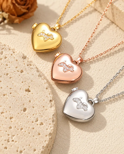 Gold tone, rose gold tone and silver tone puppy heart photo lockets stacked beside a travertine slab