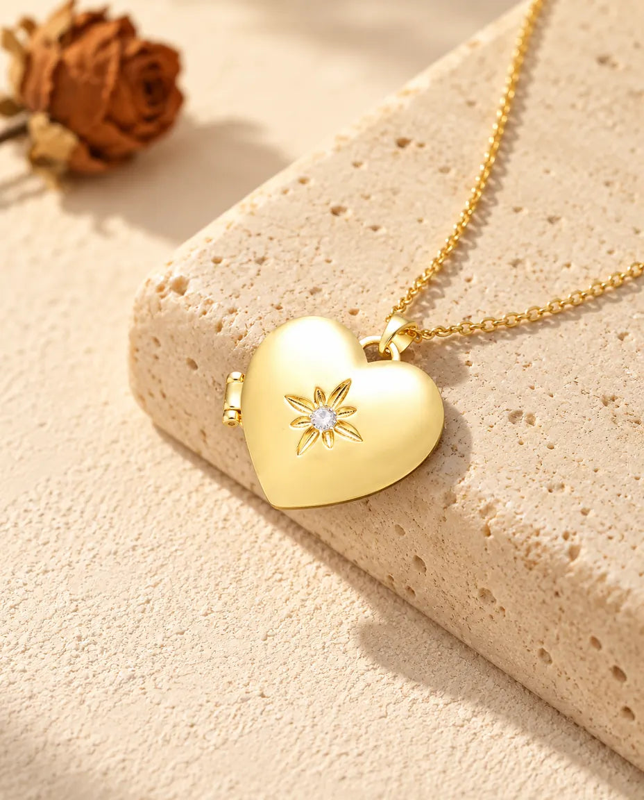 Gold tone satin flower heart photo locket necklace resting on a travertine block