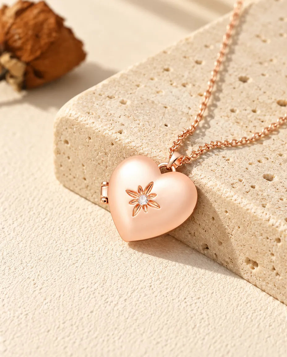 Rose gold tone satin flower heart photo locket necklace on travertine in warm sunlight