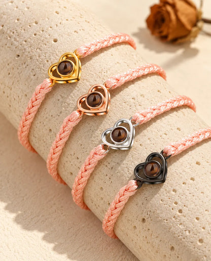 Pink braided cord open heart bracelets showing every charm color draped over travertine