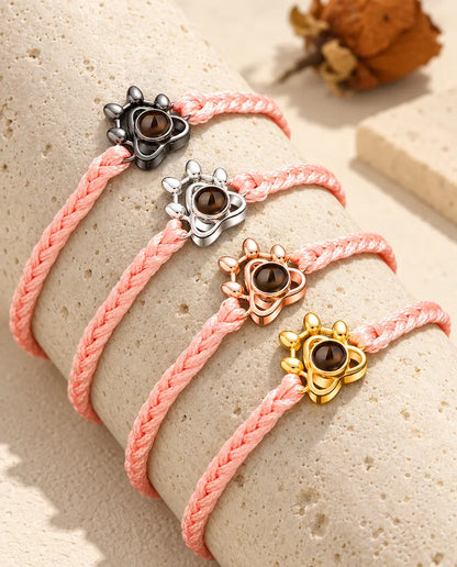 Pink braided cord paw charm bracelets showing every charm color draped over travertine