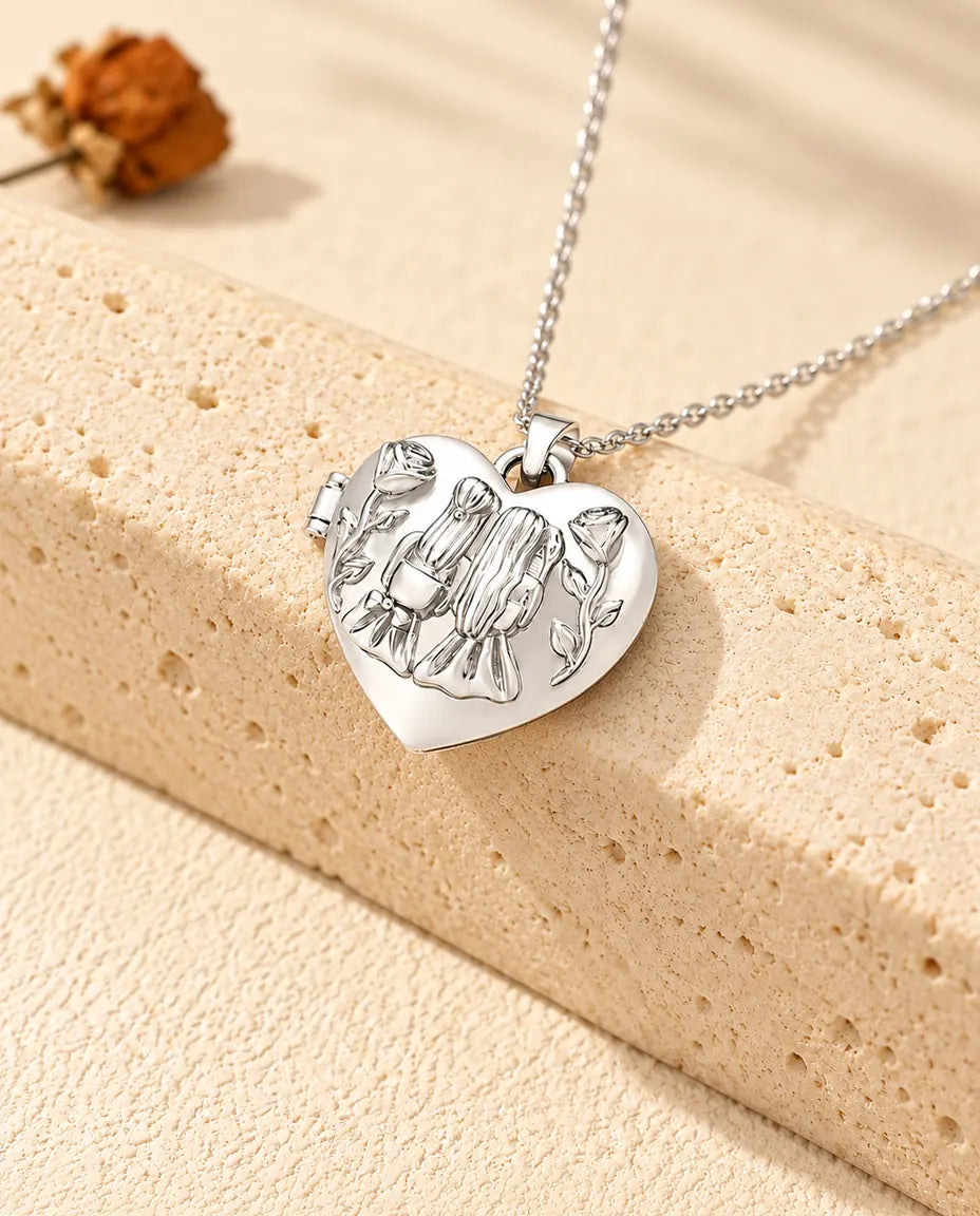 Personalized sisters heart photo locket necklace in silver tone with two girls and roses on the lid, resting on a travertine block