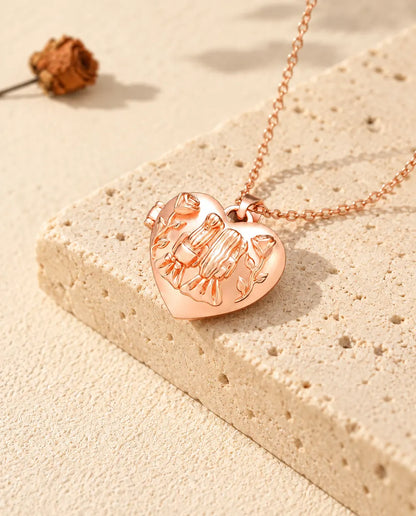 Rose gold tone sisters heart photo locket necklace on travertine in warm sunlight