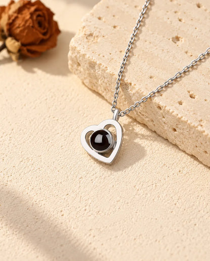 Personalized 925 sterling silver double heart photo projection necklace on cream plaster beside travertine