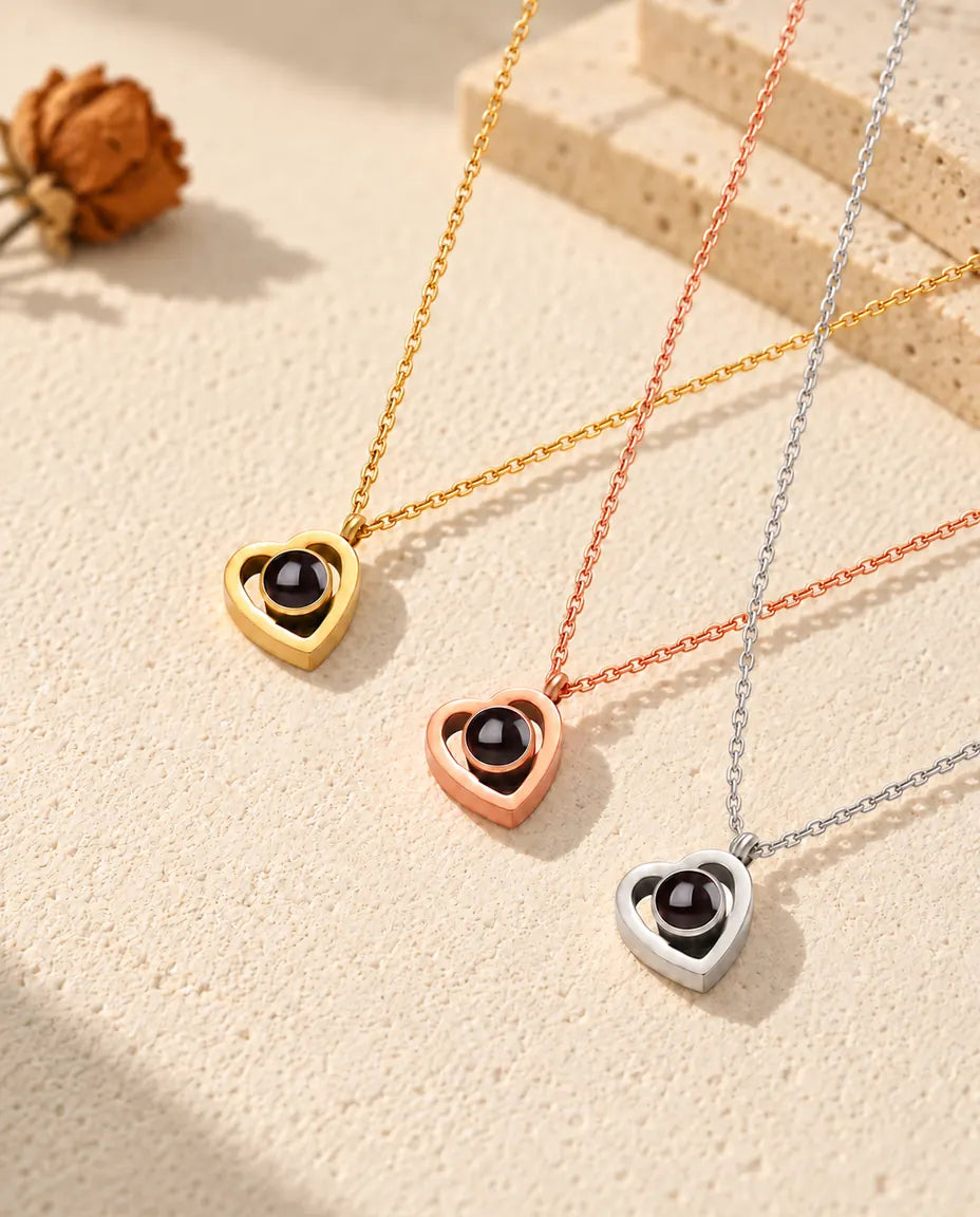 Double heart photo projection necklaces in gold tone, rose gold tone and silver laid diagonally on plaster