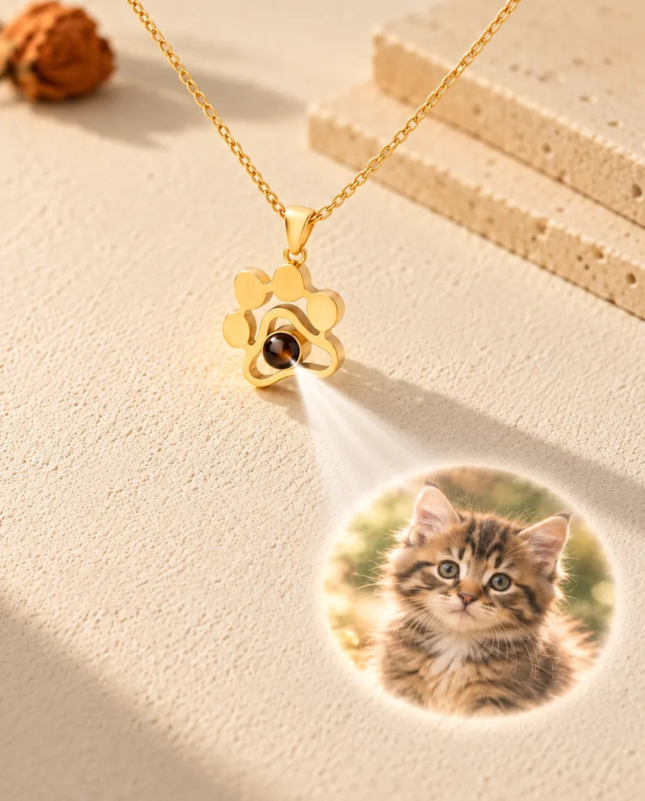 Gold tone paw print necklace projecting a kitten photo onto cream plaster