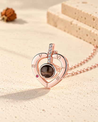 Close-up of the rose gold tone Roman numeral heart pendant with its cubic zirconia bar