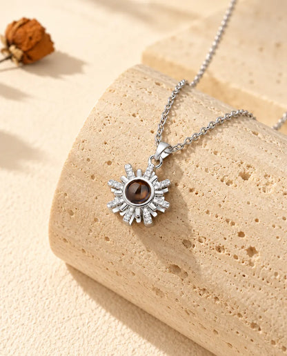 Silver tone sunburst projection necklace hanging over travertine