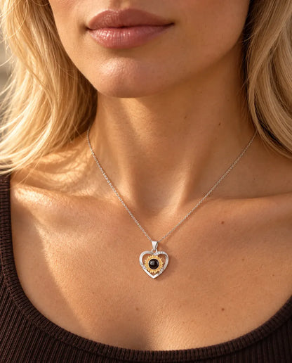 Woman in a brown knit top wearing the sunflower heart projection necklace