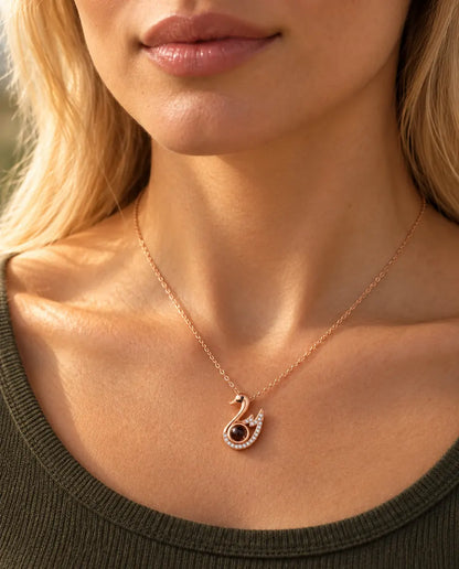 Woman in an olive green knit top wearing the rose gold tone swan projection necklace