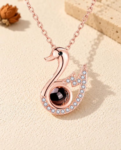 Front view of the rose gold tone swan photo projection necklace
