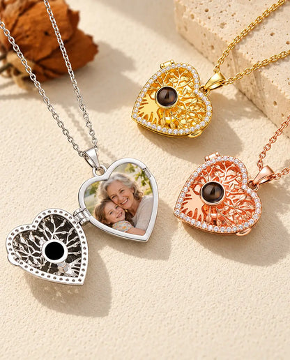 Silver tone heart locket opened like a book to show a printed photo inside, beside closed gold tone and rose gold tone lockets