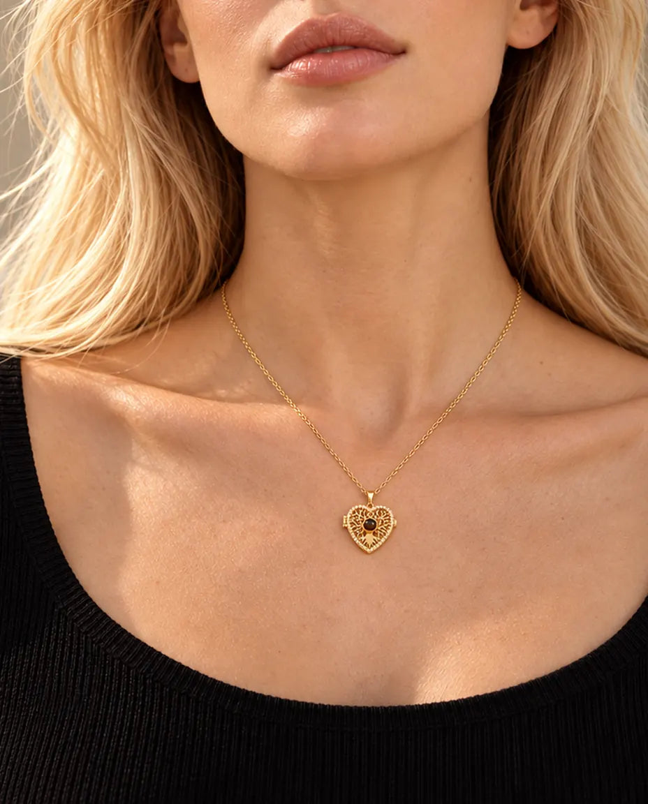 Blonde woman in a black top wearing the gold tone tree of life heart locket necklace with a projection stone