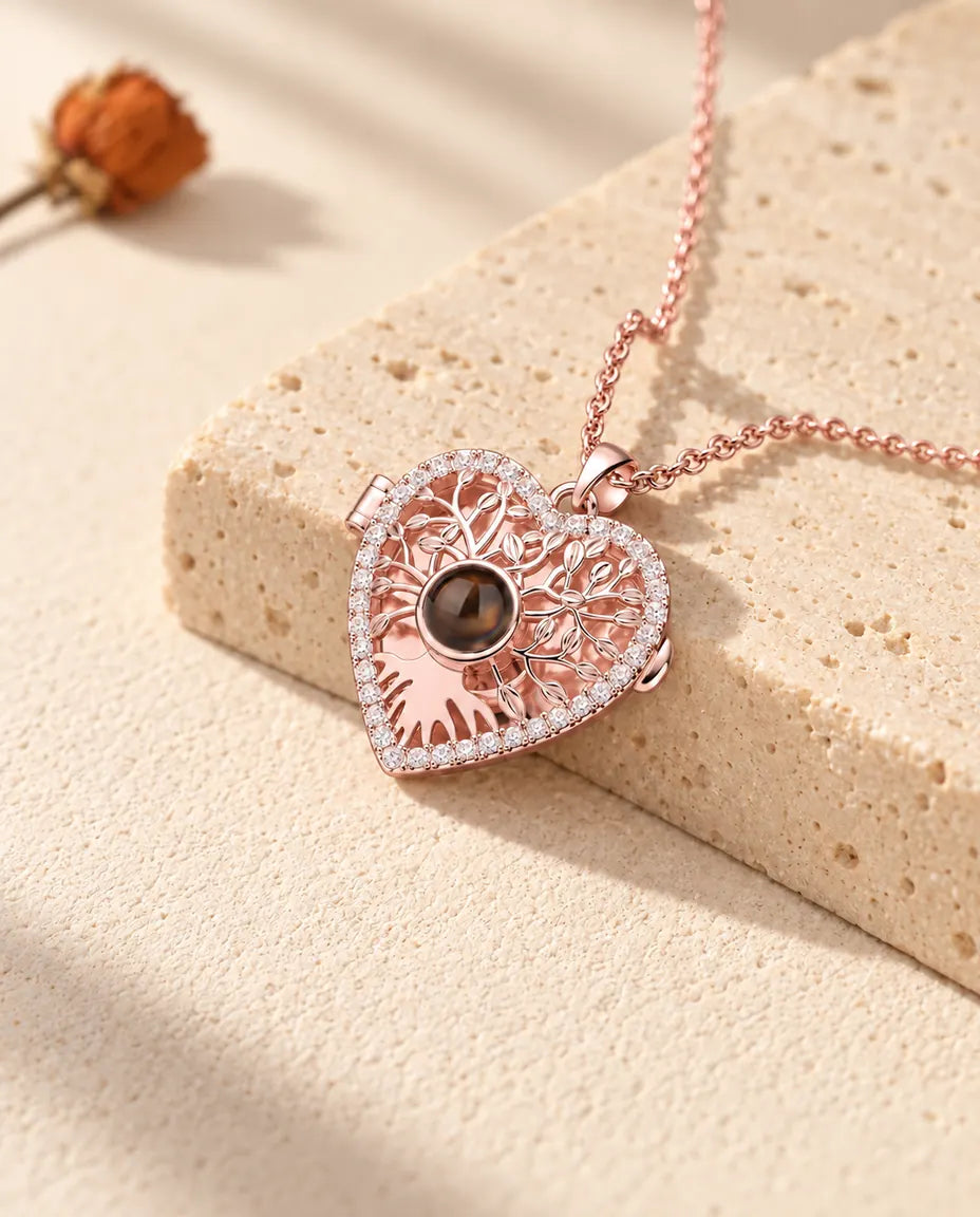 Rose gold tone tree of life heart locket necklace draped over a travertine block