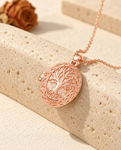 Rose gold tone tree of life photo locket with Celtic knotwork resting on travertine