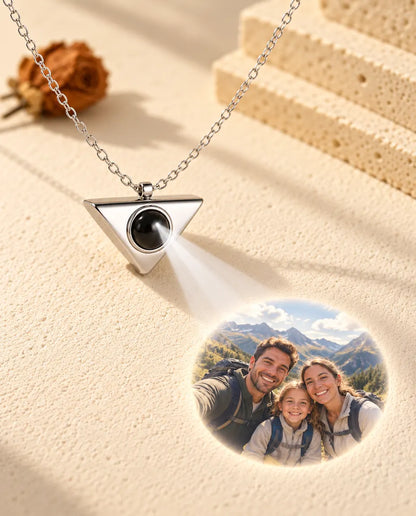 Silver tone triangle necklace projecting a family hiking photo onto cream plaster