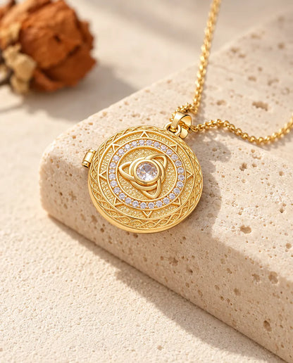 Gold tone round trinity knot locket necklace with a center stone draped over a travertine block