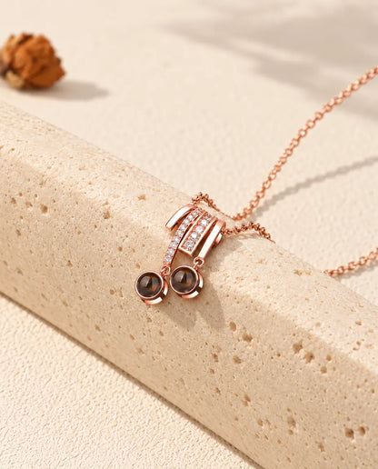 Rose gold tone two stone projection slide necklace draped over a travertine block