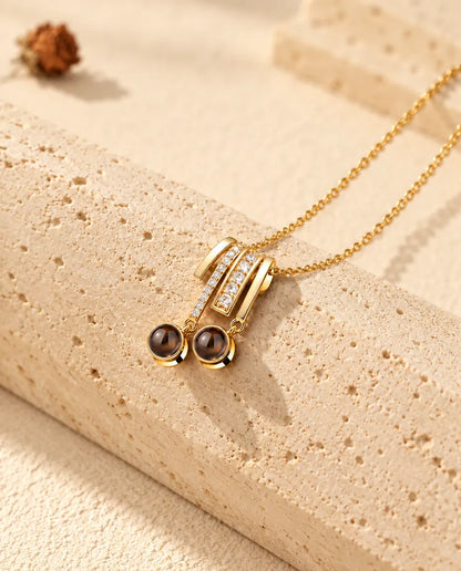 Gold tone pave slide necklace with two round projection stones resting on travertine