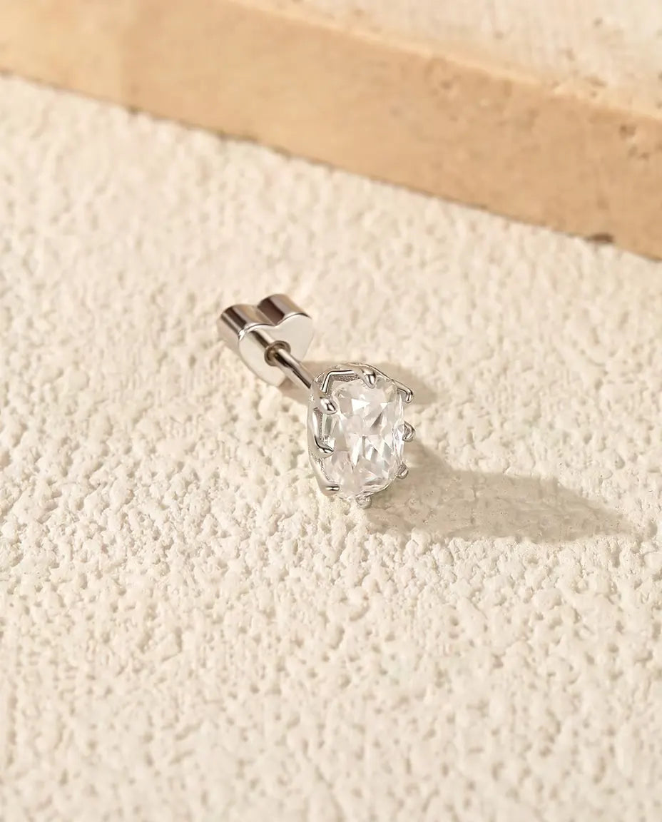 Radiant Cut Moissanite Stud Earrings in 925 Sterling Silver - lying on a cream textured surface beside a travertine slab