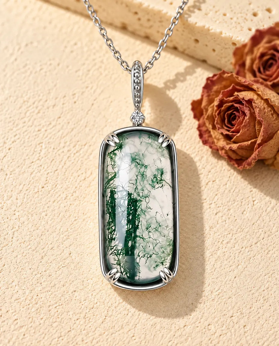 Rectangle Moss Agate Pendant Necklace in 925 Sterling Silver - lying on a cream textured surface beside a travertine block