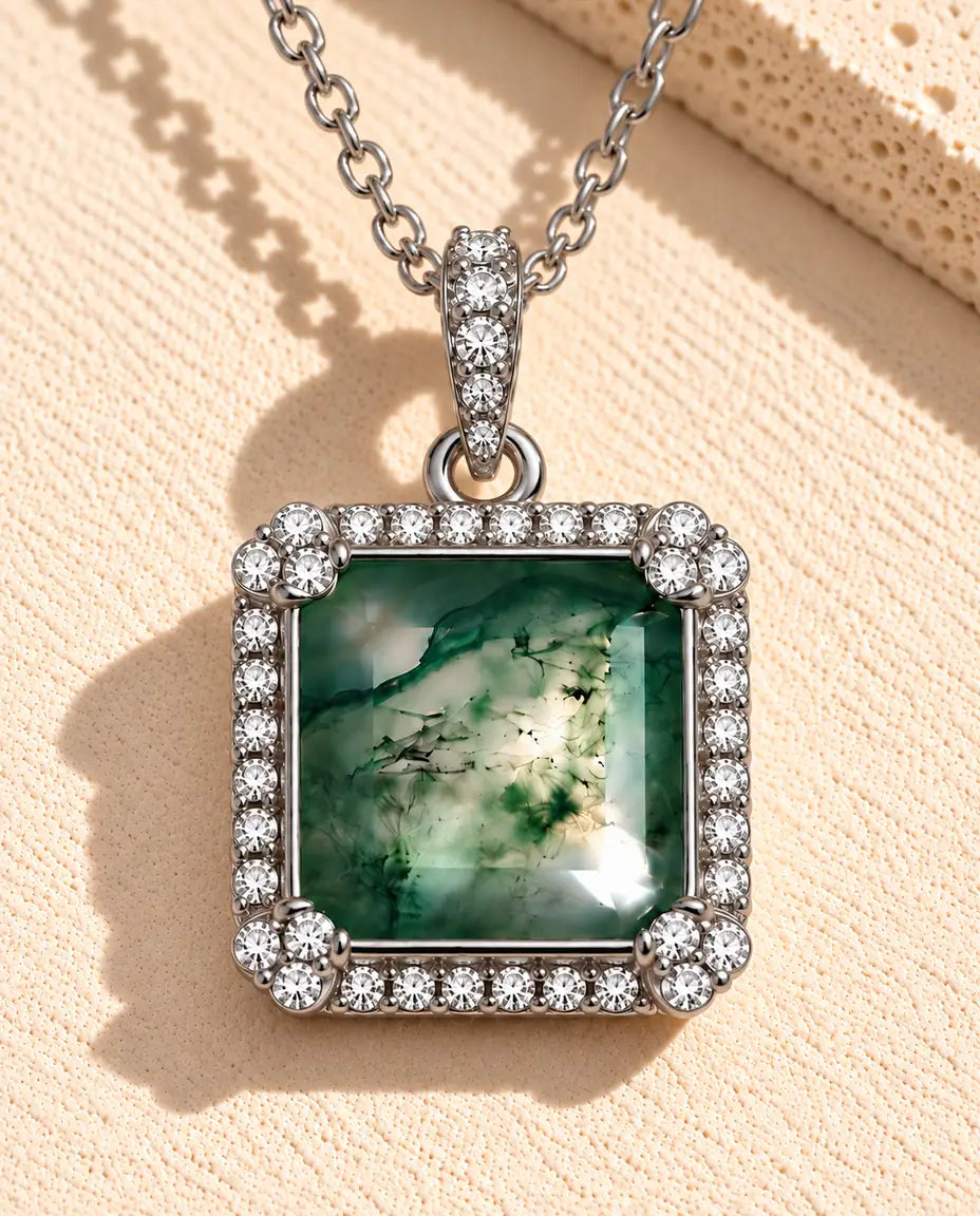 Square Moss Agate Halo Necklace in 925 Sterling Silver - lying on a cream textured surface beside a travertine block