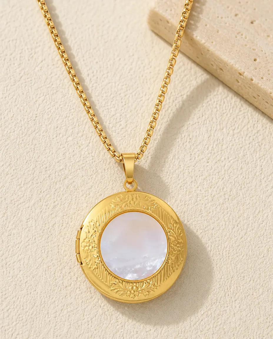 Gold round photo locket necklace with a white mother of pearl centre and embossed floral border