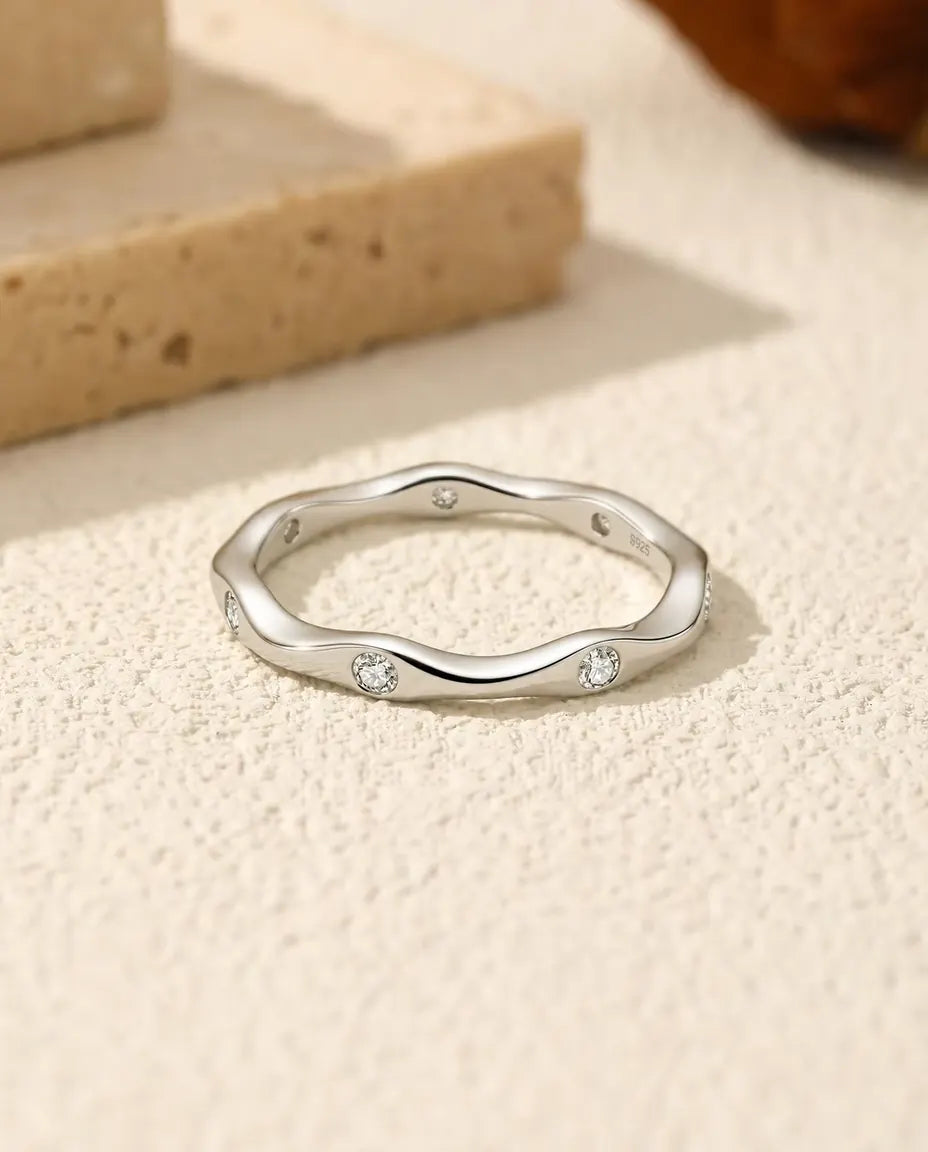 Wavy Moissanite Band Ring in 925 Sterling Silver - lying flat on a cream textured surface